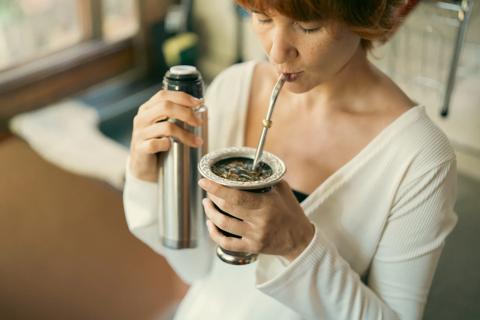 Person sipping a beverage in a metal cup through a metal straw
