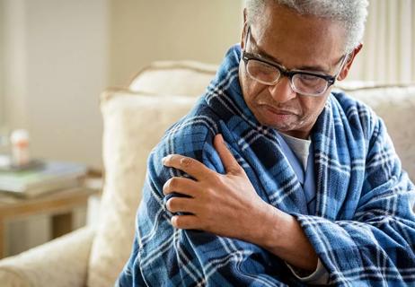 Older man rising from bed with shoulder pain