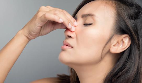 Person holding bridge of their nose, with their eyes closed