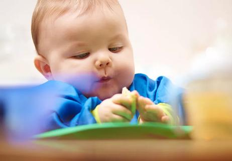 Baby feeding himself bits of toast