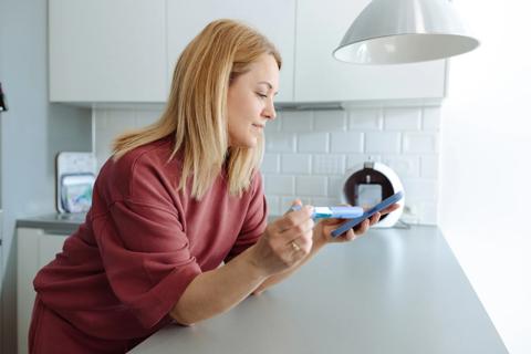Person leaning on kitchen counter, reviewing semaglutide injection