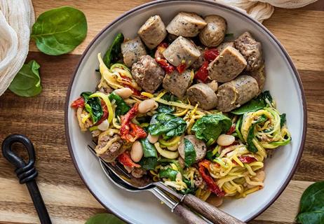 Zucchini noodles mixed with sun-dried tomatoes and chunks of sausage