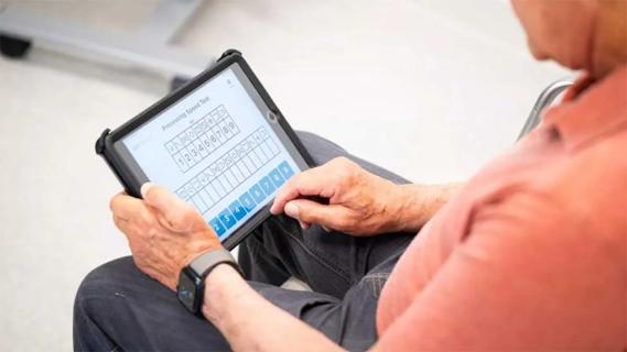 A man looking at a cognitive screening tool on a tablet.
