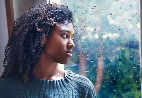 woman looking out rainy window