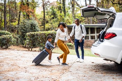 Happy family packing luggage into vehicle for a trip