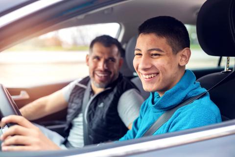 Adult in the passenger seat of car while smiling teen drives
