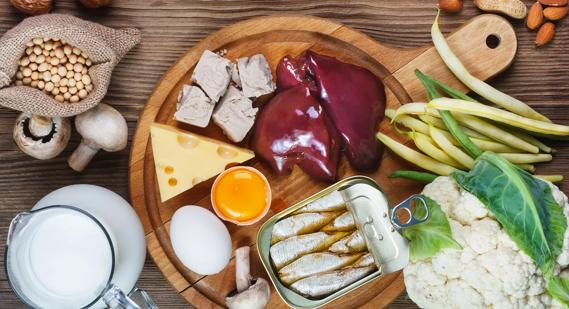 Biotin-rich foods, like liver, sardines, mushrooms and cheese, on wooden serving tray