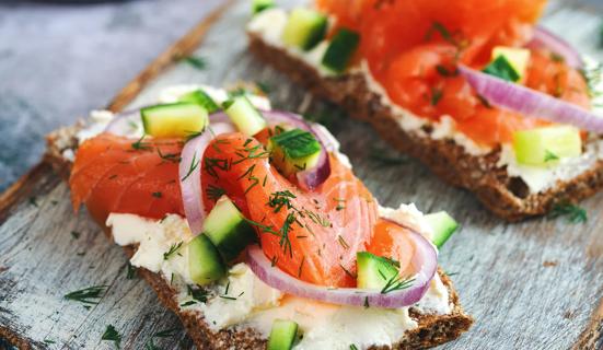 Salmon topped with sliced cucumbers and onion on cheese and toast