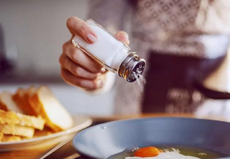 cook adding salt to food