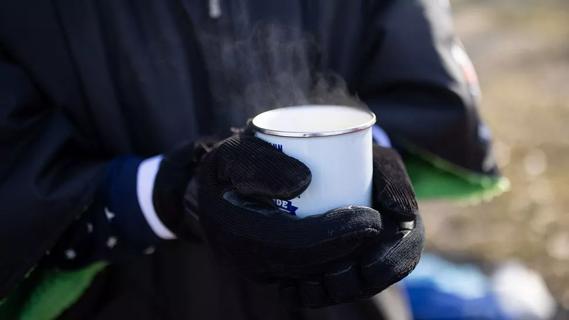 Close up of gloved hands holding hot drink, steaming mug, outside in the cold