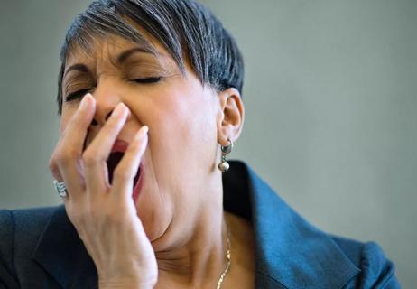 Closeup of older business person yawning into hand.