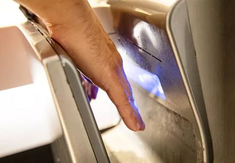Someone uses a wall-mounted jet dryer to dry their hands.