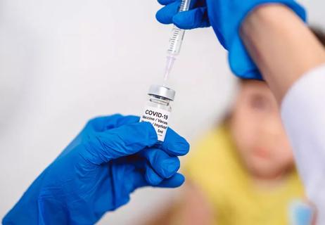 doctor holding covid-19 vaccine vile in front of a child