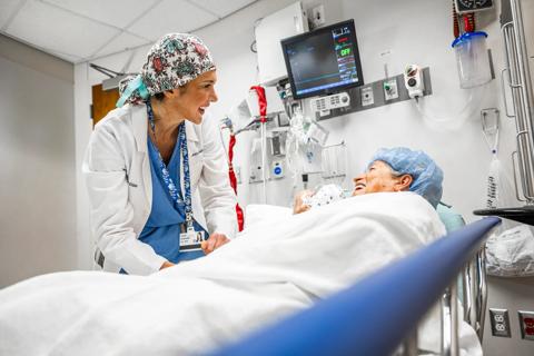 Dr. Bukavina smiles at patient in hospital bed