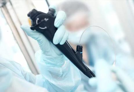 Healthcare provider in surgical gloves and gown holding endoscope