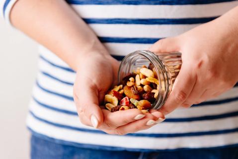 Person pouring homemade trail mix from jar into their hand