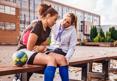 Trainer checks on injured athlete at school