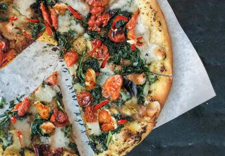 Pizza with pesto, chicken, tomatoes, cheese and red peppers.