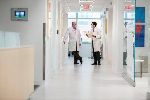 Two physicians standing at the end of the hallway talking