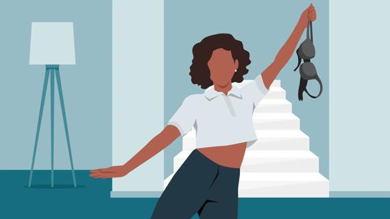 Woman at home holding up her bra that she's taken off