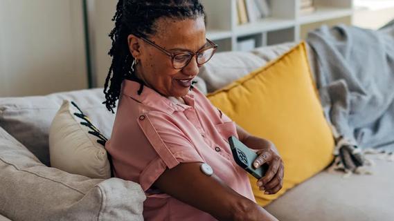 Woman using phone to read her continuous glucose monitor
