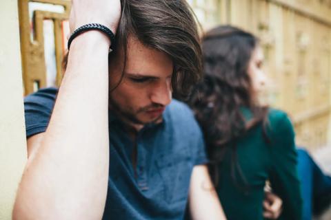 A couple sitting together, looking sad/distressed