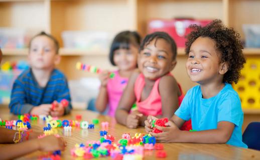 Smiling preschoolers at school table with colorful snapping blocks