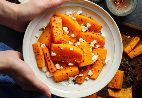 Roasted butternut squash on white plate with feta cheese garnish.