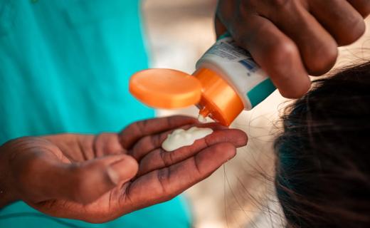 Hand squeezing sunscreen from a tube into other hand