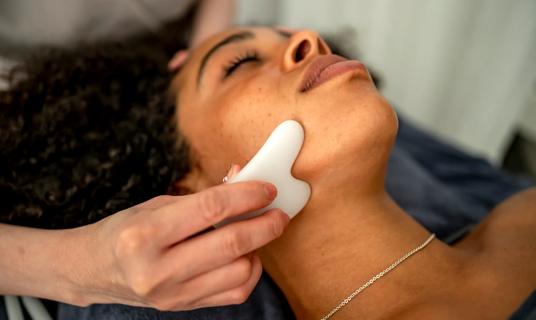 Person receiving a gua sha facial massage
