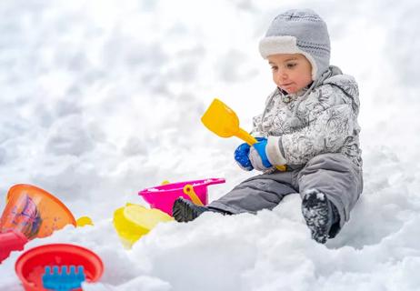 child plays in snow with sand toys