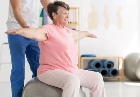 Elderly woman practicing balance with physical therapist providing support