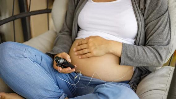 Pregnant woman looking at glucose pump