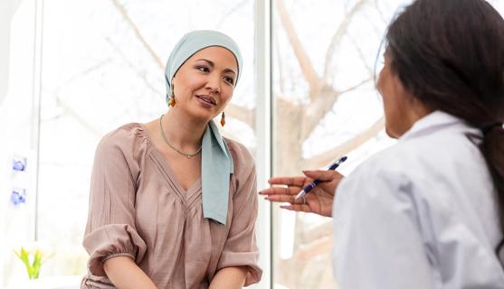 Patient wearing head scarf for cancer talking with healthcare provider