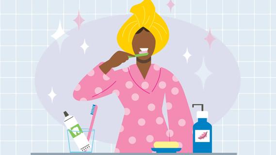 Person in robe, hair wrapped in a towel, brushing their teeth at bathroom sink