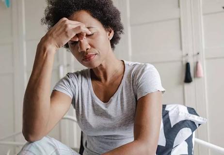 Woman pinching nose, expressing pain or discomfort.