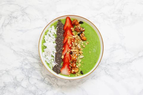 Green smoothie bowl with strawberries, granola, seeds and coconut