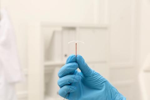 copper IUD device being held by a gloved hand