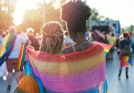 Two people wrapped up in a rainbow flag