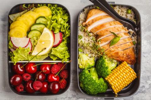Meal trays of grilled chicken, grains, vegetables, and fruit