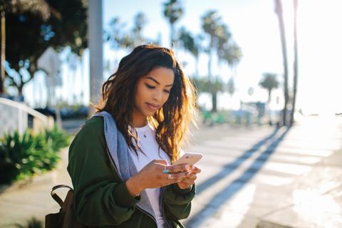 Person walking outdoors, looking at smartphone