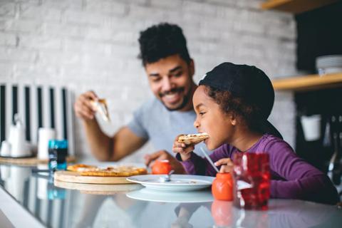Caregiver and child eating pizza together