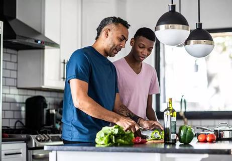 Father and child preparing a salad in kitchen.