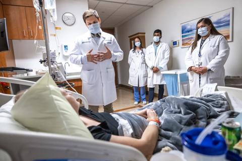 Doctor and team talking to patient in hospital bed