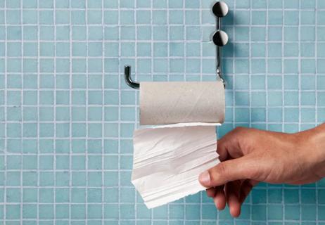 Hand in bathroom grabbing last of toilet paper