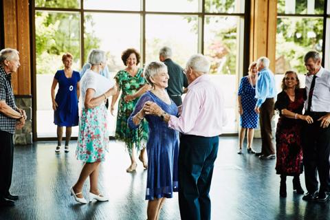 Smiling couple holding hands and finishing dance in community center