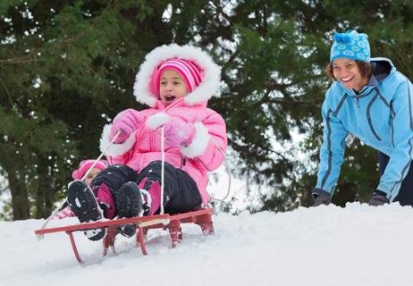 mom and daughter sledding during winter