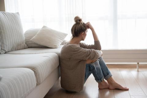 Woman sitting on living room floor looking toward window