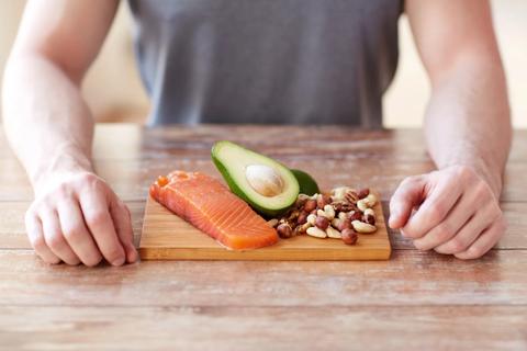 Keto-friendly proteins on cutting board, with salmon, avocado and mixed nuts