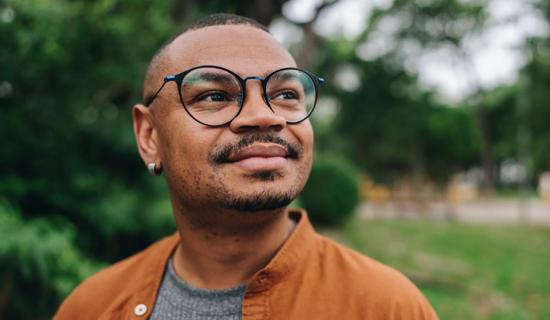 Person wearing glasses outdoors, looking around